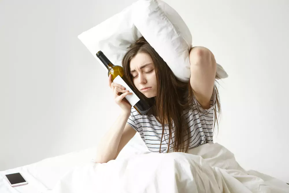 Woman Suffering From Bad Hangover Holding Bottle Of Wine