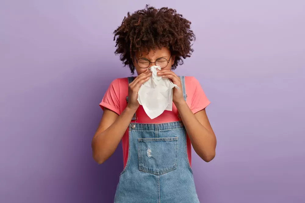 Young Female Feels unwell blows Nose